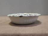 a white bowl sitting on a table with a brown table cloth