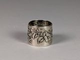 silver ring with flowers and leaves on it on a white surface