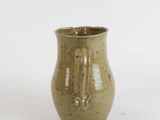 a small green vase with a handle on a white surface
