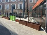 un immeuble doté d'une façade vitrée et d'une clôture métallique donnant sur le trottoir