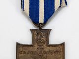an old medal with a cross on it sitting on top of a white table