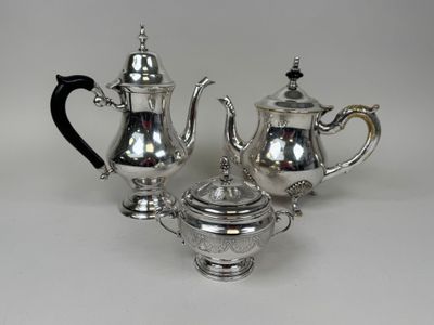 three pieces of silver tea and coffee set on a white surface