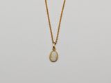 a gold necklace with a white stone pendant on a gold chain