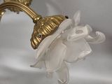 a white flower that is on a gold wall sconce