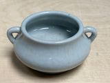 a small blue pot sitting on a wooden table