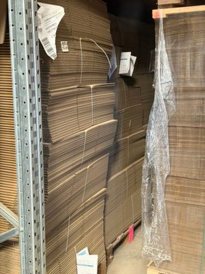 une grande pile de cartons dans un entrepôt où se trouvent de nombreuses palettes