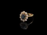 gros plan d'une bague en or avec un saphir et des diamants