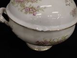 a white bowl with pink flowers on it on a black surface