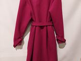 a red coat hanging on a wall next to a white wall