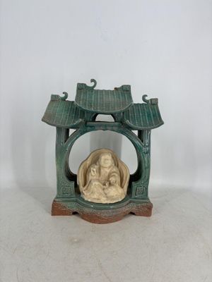 une petite statue représentant une personne assise dans un petit sanctuaire