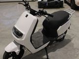 un scooter blanc garé dans un garage à côté d'autres voitures