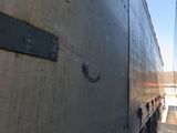 a truck that is parked under a bridge in the day