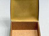 a small green box with a gold lid on a white surface