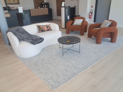 a living room with a couch, chair, coffee table and kitchen in the background