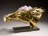 sculpture of a golden horse with a flower on its head