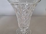 a glass vase sitting on a table with a clock in the background