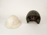 two helmets are sitting on a white surface, one is green and the other is white