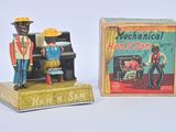 two figurines of a man playing a piano and a man in a hat
