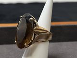 bague en or sertie d'une pierre de smokyite, posée sur un cône blanc, sur une table