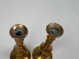 two brass candlesticks on a white table
