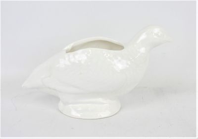 un vase en forme d'oiseau blanc posé sur une surface blanche
