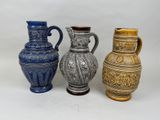 three different colored vases sitting next to each other on a white surface