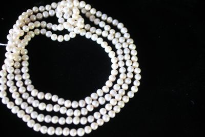 un gros plan sur un collier de perles blanches posé sur une surface noire