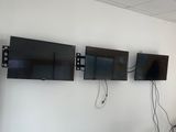 trois téléviseurs fixés au mur dans une pièce