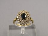 an image of a gold ring with a blue stone surrounded by white diamonds