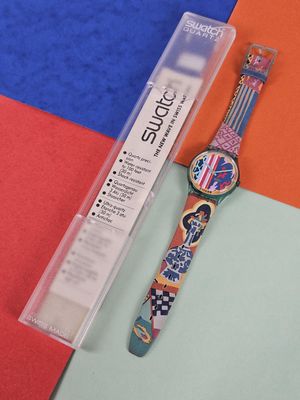 a watch sitting on a colorful surface next to a plastic box