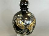a black and gold vase sitting on a white surface