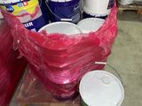 de nombreux seaux de peinture posés sur une palette dans un entrepôt