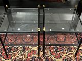 une paire de tables basses en verre et en laiton posées sur un tapis