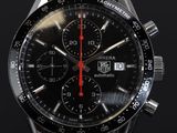 une montre noire avec une trotteuse rouge sur fond noir