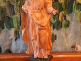 une statue représentant un homme tenant un livre posé sur une table