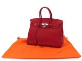 a red handbag sitting on top of an orange blanket
