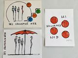 trois cartes représentant des personnes et un parapluie, accrochées sur un réfrigérateur