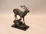 sculpture en bronze représentant un cerf debout sur un rocher, sur fond blanc