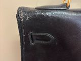someone is holding a black bag with a handle on a wooden table