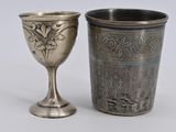 a silver cup next to a silver cup on a table