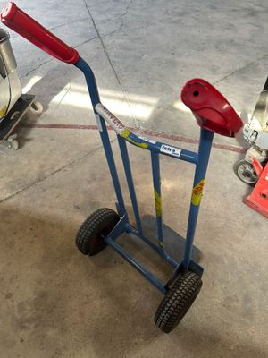 un diable bleu avec une poignée rouge dans un garage