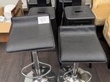 four black leather stools and a chair in a room