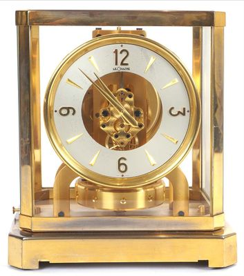 a gold clock with a white face on a white background