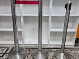 three stainless steel poles with red ribbon on them in front of a bookcase