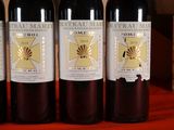 three bottles of red wine are lined up on a table
