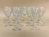 six verres à vin transparents sont alignés sur une table