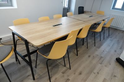 a long table with yellow chairs and a laptop on it