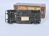 a black toy train on a white surface with a box in the background