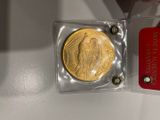 une pièce d'or dans un étui en plastique transparent muni d'une étiquette rouge