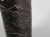 an image of a black vase with a mountain scene etched on it